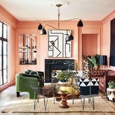 a living room filled with lots of furniture next to a fire place in a pink wall