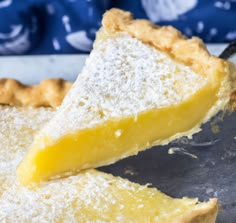 a piece of lemon pie with powdered sugar on top is being held by a spatula