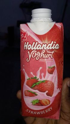 a hand holding a carton of yogurt with strawberries