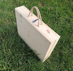 a wooden bag sitting on top of a lush green grass covered field next to a fence