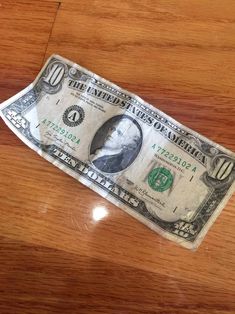 a one dollar bill sitting on top of a wooden table