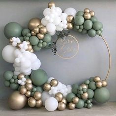 the balloon arch is decorated with gold, white and green balloons