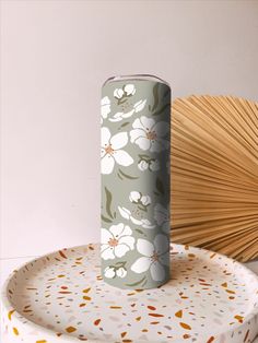 a paper plate with a flower pattern on it and a bamboo fan in the background