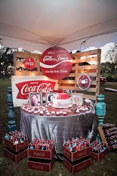 a table with coca - colas and other items on it in front of a sign