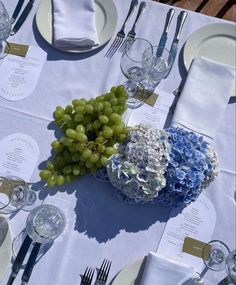 the table is set with blue and white flowers, silverware, and wine glasses