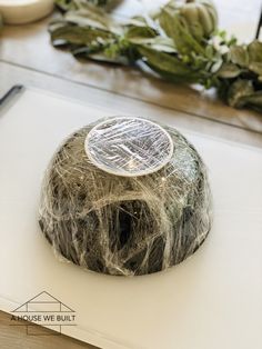 a rock covered in silver foil sitting on top of a cutting board next to some plants