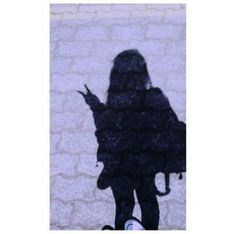 the shadow of a person standing in front of a white brick wall holding an umbrella