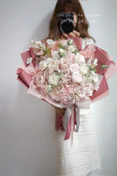 a woman holding a bouquet of pink and white flowers in front of her face while taking a selfie