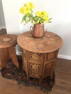 two wooden tables with flowers in a vase on top of one table and another side table