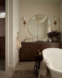 a bath room with a tub a mirror and a rug on the floor in front of it