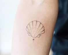 a small tattoo on the arm of a woman with a seashell in it's center