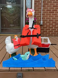 a duck with life vest and two ducks in front of a house