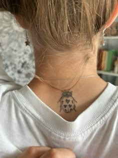 a ladybug tattoo on the neck of a woman's upper back neck