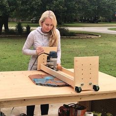 a woman is working on a project with a table saw and driller in front of her