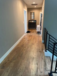 an empty hallway with hard wood floors and gray walls