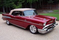 an old red car is parked in the driveway