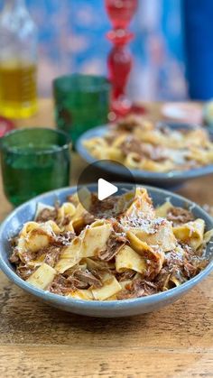 a bowl full of food sitting on top of a wooden table next to two glasses