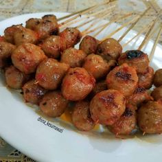 meatballs on skewers sitting on a white plate