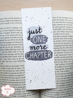 a bookmark with the words just one more charter on it, sitting in front of an open book