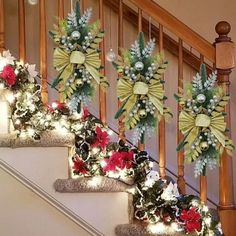 christmas decorations are on the banisters at the bottom of the stair case, decorated with holly and poinsettia