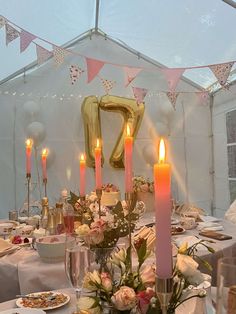 the table is set with flowers and candles for an elegant dinner or party event in a marquee