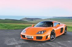 an orange sports car is parked on the road