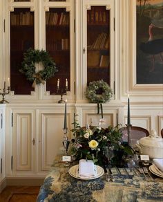 a dining room table is set with place settings and flowers on the centerpieces