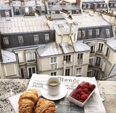 some croissants and raspberries on a newspaper with a cup of coffee