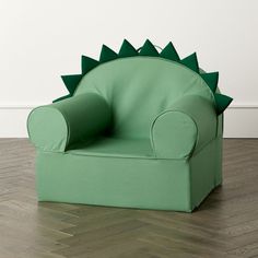 a green dinosaur chair sitting on top of a hard wood floor