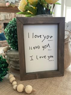 a wooden frame sitting on top of a table next to a vase filled with flowers