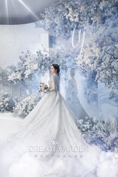 a woman in a white wedding dress standing next to a blue and white wall with flowers