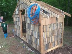 a small wooden shed with blue ropes on the roof and two children in the background