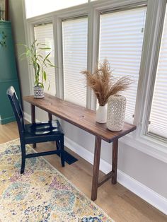 a wooden table with two vases on top of it next to a blue chair