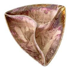 a decorative bowl with pink and gold designs on the outside, in an irregular shape