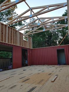 the inside of a house being built with red walls and wooden beams on top of it