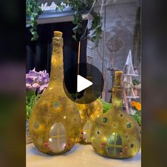 two vases with holes in them sitting on a table next to flowers and plants