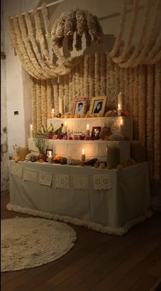 a table with candles and pictures on it in front of a wall hanging from the ceiling