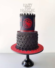 a black and red birthday cake with a game of throne logo on it's side