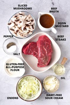 the ingredients to make beef chops laid out on a marble counter top, including mushrooms, broth, garlic, and seasoning