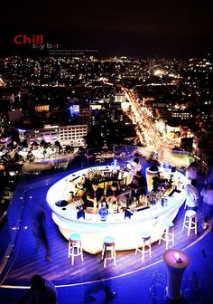 an aerial view of the city at night, with people sitting and standing around it