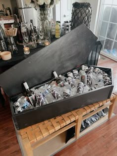 a wooden table topped with lots of bottles and glasses next to a vase filled with flowers