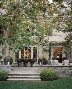 a house with stone steps leading up to the front door and covered in potted plants