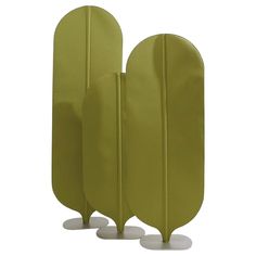 three green surfboards are lined up against each other on white bases and stand upright