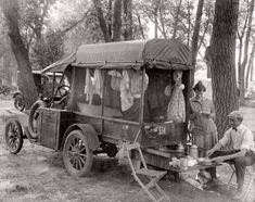 an old timey photo of people sitting in front of a truck with laundry hanging on it