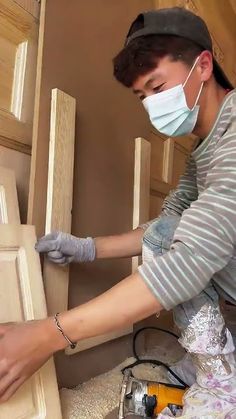 a woman wearing a face mask and gloves working on cabinets