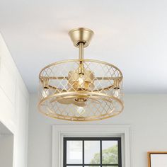 a gold ceiling light fixture in a white room with a large window and framed pictures on the wall