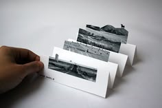 a hand is holding some cards with black and white pictures on them, which are folded in half