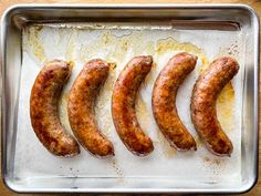 four sausages on a baking sheet ready to be cooked in the oven for dinner