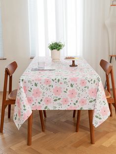 the table is covered with a pink and green flowered tablecloth, along with two wooden chairs