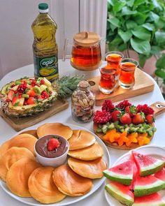 a table topped with lots of different types of fruit and pastries on top of plates